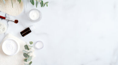 Set of organic cosmetic products and eucalyptus leaf on marble background. Flat lay, top view. Beauty and body care concept